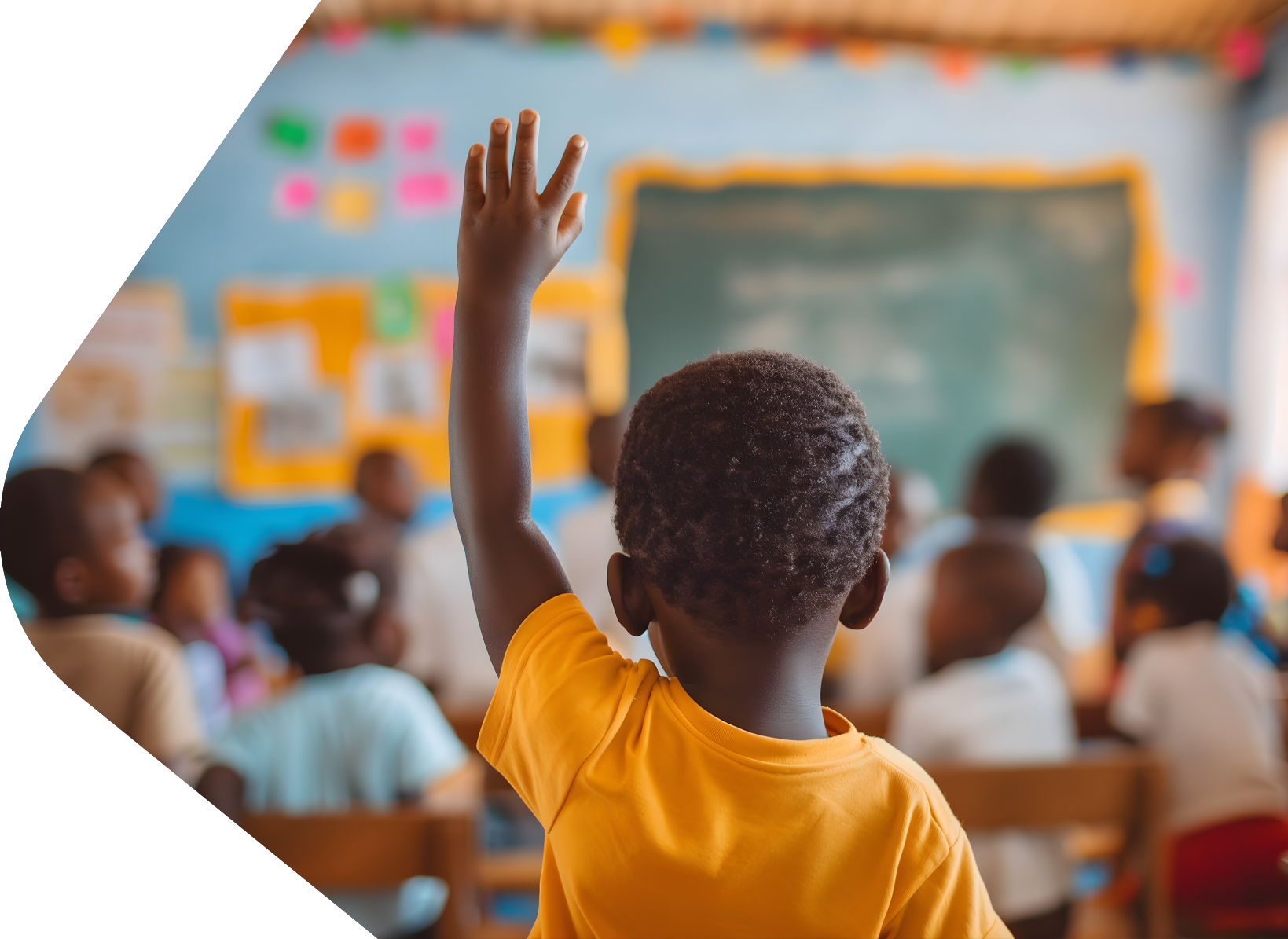 Young child with orange t-shirt sitting in school class with his arm raised answering questions