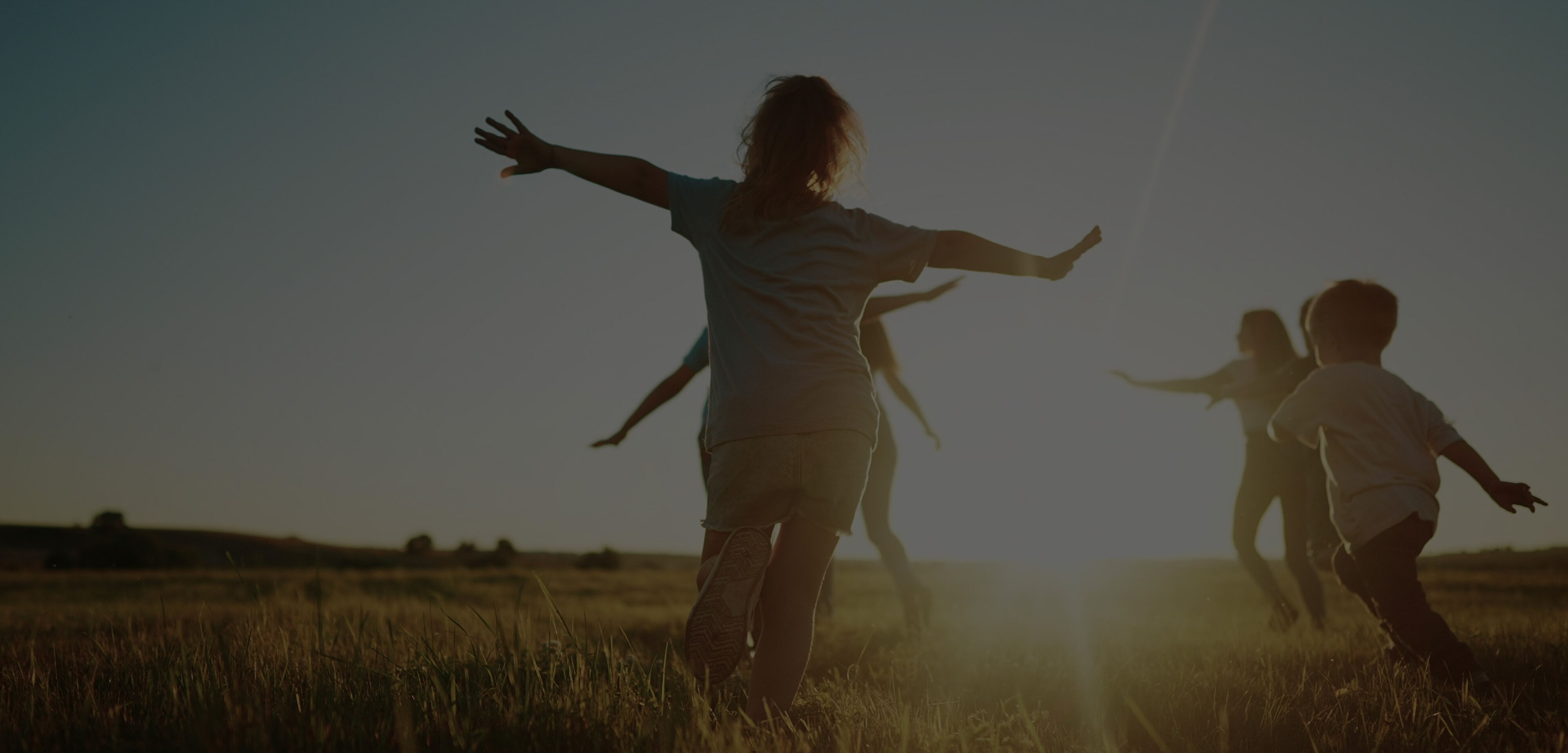 Group of children racing through a park at sunset