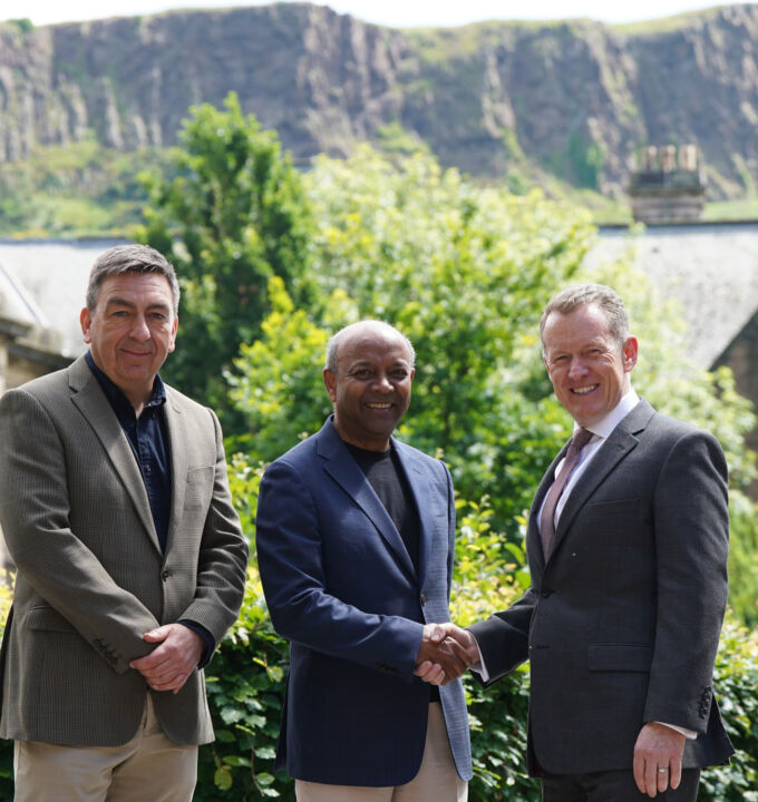 Three Childlight professionals stand together, with Edinburgh's Arthur Seat Hill in background