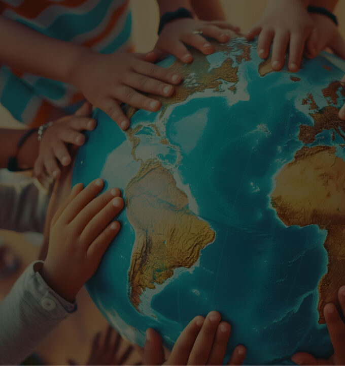 A classroom of children from various races lay their small hands on a large globe of the world