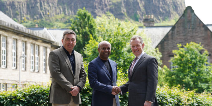 Three Childlight professionals stand together, with Edinburgh's Arthur Seat Hill in background