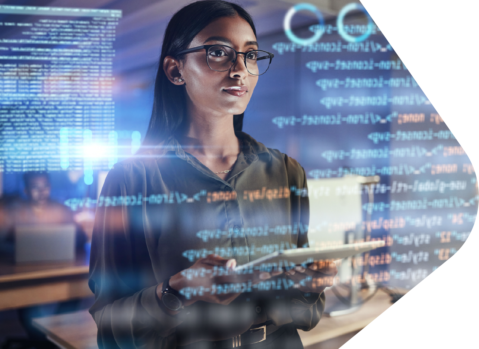 Older Indian female stands in a busy office with computer screen reflecting text across the whole image