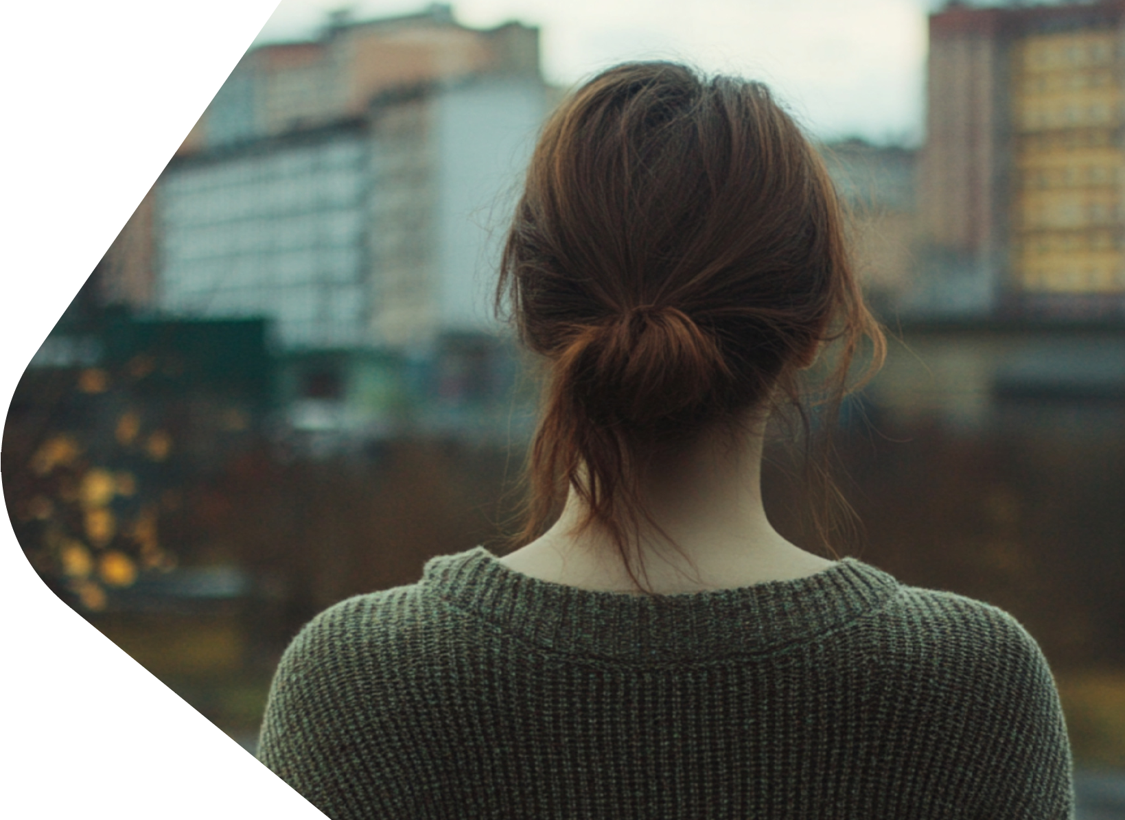 Young adult facing towards blocks of flats with her back to the camera